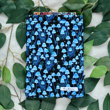 Load image into Gallery viewer, Moonlight Magic has a book peeking out of the sleeve, pictured in flat lay style. There are leaves underneath working as a background.