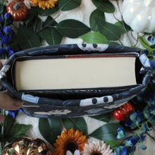 Load image into Gallery viewer, A picture taken from birds-eye-view is showing how a thick hardcover book fits into a medium-sized book sleeve.