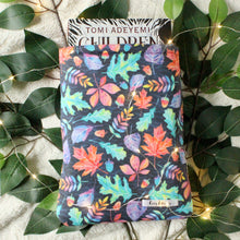 Load image into Gallery viewer, Hardcover book of Children of Blood and Bone by Tomi Adeyemi in a Medium sized Autumn Leaves book sleeve. Picture is head on directly above