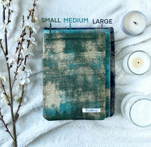 Load image into Gallery viewer, Small, Medium, and Large book sleeves are laid on top of one another to show another difference between the sleeves. Text with the matching book sleeve is shown to indicate which size correlates to exact book sleeve.