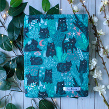 Load image into Gallery viewer, A medium-sized Green Forest Guardian sleeve is pictured. Within the fabric design there are cats with white eyes, green, white and pink forest flora, and tiny long-haired folk are also depicted as well. Tiny folk are either beside, or on, the cats.