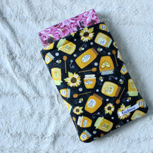 Load image into Gallery viewer, Honey Jars is laid flat on a white textured bacground. There's a book halfway in the book sleeve.