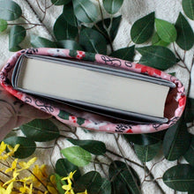 Load image into Gallery viewer, Photo taken from a birds-eye-view perspective showing how a medium sized hardcover book fits in a Medium-sized book sleeve.