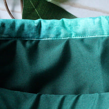 Load image into Gallery viewer, The Forest book sleeve is being held open. Inside we can see a rich green fabric that lines the inside of the Forest book sleeve.