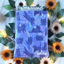 Load image into Gallery viewer, Pictured is a medium-sized Purple Forest Guardian book sleeve. Inside the book sleeve is a hardcover book of "Children of Blood and Bone" by Tomi Adeyemi.