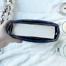 Load image into Gallery viewer, A hand is holding a large-sized Indigo Gold Dust book sleeve. Inside the sleeve a thick hardcover book sits.