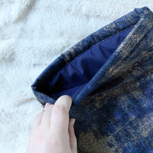Load image into Gallery viewer, A hand is holding open Indigo Gold Dust. There's a dark blue fabric inlay inside the sleeve.