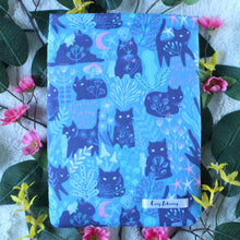 Load image into Gallery viewer, Forest Guardian as a Small sized book sleeve is shown. Throughout the photo there are pink and yellow flowers. There are leaves beneath everything. There are no fairy lights in this photo.