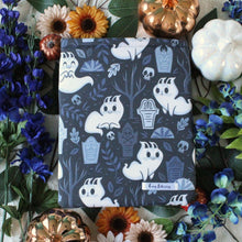 Load image into Gallery viewer, Cartoon Ghost cats are shown in a graveyard. Some are smiling, some are not. There are leaves and headstones, skulls and leaf-less trees also in the design. Fabric is a repeated design.