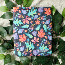 Load image into Gallery viewer, Autumn Leaves in a repeat pattern in cooler warm tones on fabric. Medium sized sleeve on top of a pile of leaves/