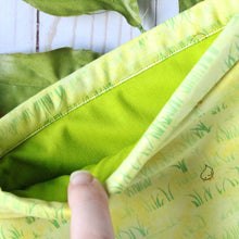 Load image into Gallery viewer, Chirp is being held open by a finger, which shows a light vibrant green fabric inlay.
