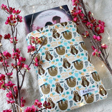 Load image into Gallery viewer, A hardcover book titled &quot;Wicked Fox&quot; by Kat Cho is shown halfway inside a small sized Born to Be Mild book sleeve. In the fabric design there are sloths. One is sitting with its arms in front of it, and the other sloth is hanging from a tree branch. There are yellow and blue flora in the fabric design as well. &quot;Born to Be Mild&quot; in Yellow text is also in the fabric design. The pattern is a repeat pattern. 
