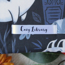 Load image into Gallery viewer, A close up of the Cozy Library tag is shown on the bottom right corner of a Ghost Kitties book sleeve.
