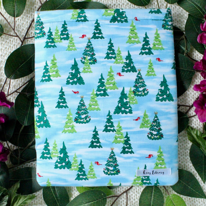 A Rudolph's Christmas book sleeve is pictured amongst Green leaves, and purple flowers.