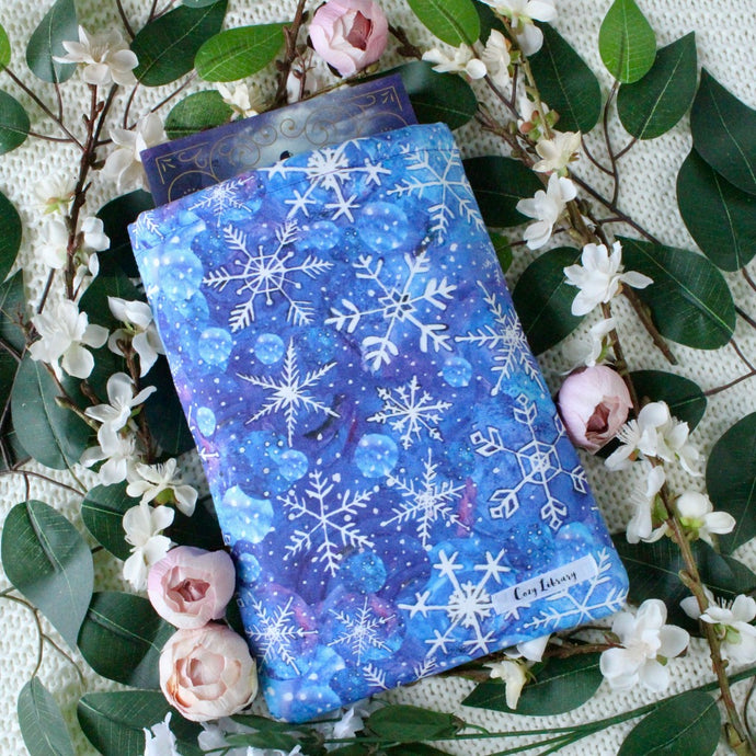 A book is partially inside a Watercolour Snowflakes book sleeve.